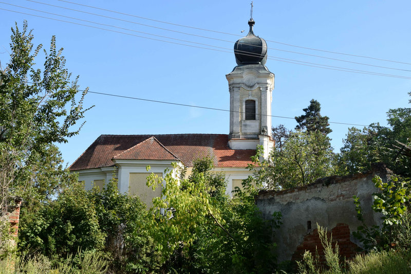 Ötvös barokk temploma észak felől, az elhagyott, egykori Szegedy-Széchenyi kúria kapujából (Fotó: Simon Anna, 2025. augusztus)